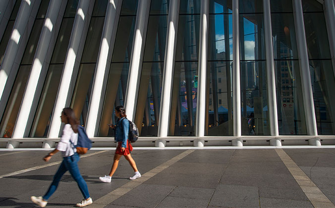 Pedestrians walk outside on Memorial Plaza at the World Trade Center in New York City